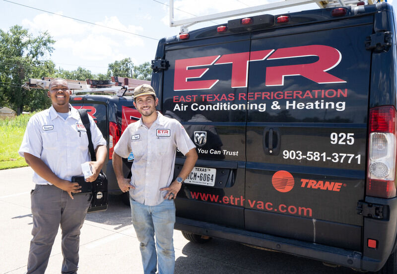 hvac system technicians standing in front of their ac service trucks