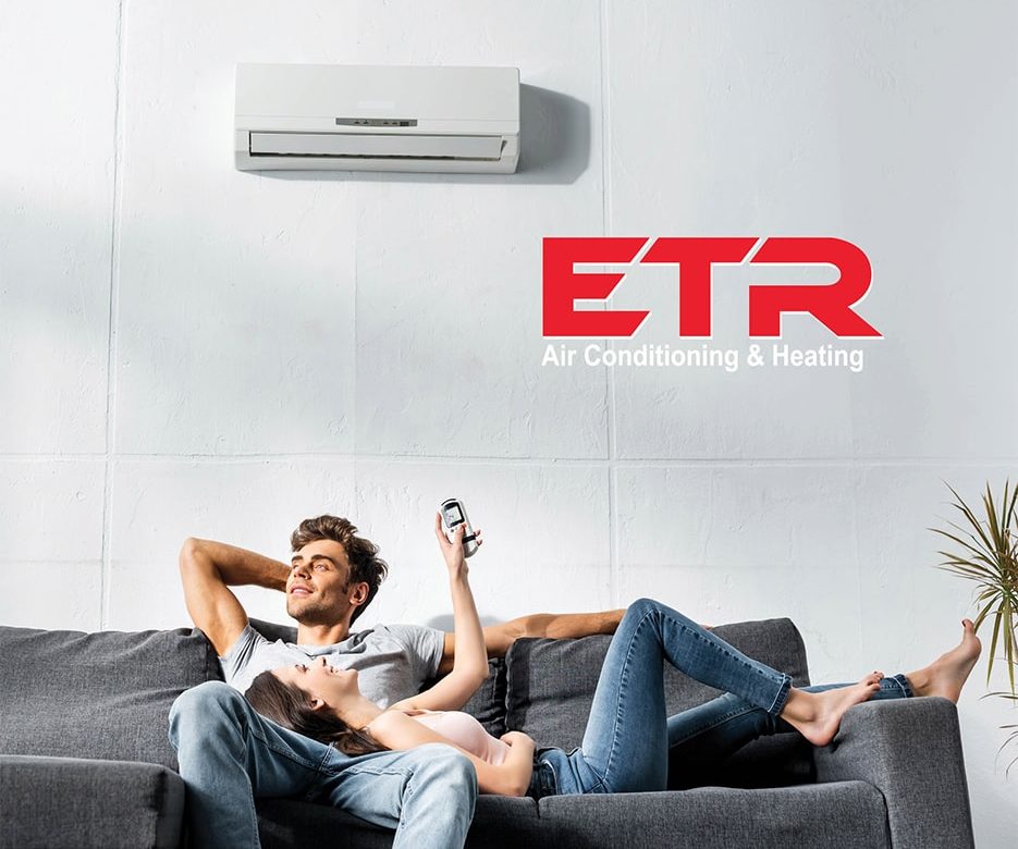 a couple is lying on a couch. a white aircondition and ETR logo are on a white wall above them.